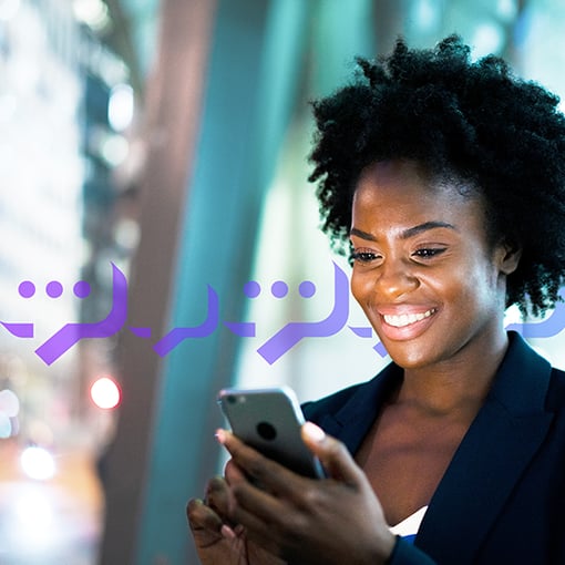 Photo of a smiling woman typing a text into her cell phone. 